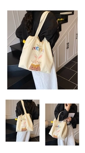 Detail of beige canvas tote bag showing drawstring closure and colorful bunny embroidery