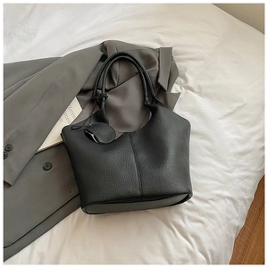 Close-up of black leather tote bag with lychee texture and round charm coin purse