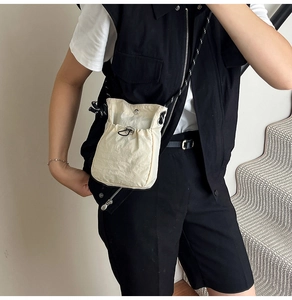 Détail du petit sac bandoulière en nylon crème avec cordon et sangle rayée élégante