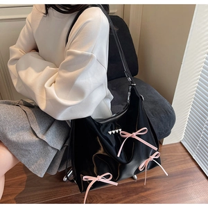 Detail of black glossy Hobo bag with pink satin bows and silver heart-shaped studs
