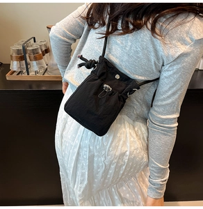 Détail du petit sac à bandoulière en nylon noir avec cordon de serrage et texture