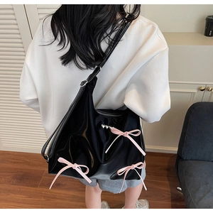 Detail of black glossy tote bag featuring pink satin bows and silver heart rivets detail