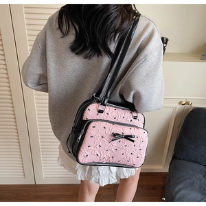 Rear view of a pink bow patterned shoulder bag worn by model showing fit and scale