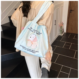 Detail of light blue polka dot drawstring tote bag featuring a cute cartoon character
