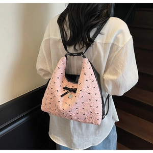 Detail of pink embossed tote with black ribbon bows and heart pendant on shoulder