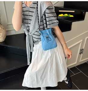 Détail du petit sac bandoulière en nylon bleu clair avec fermeture à cordon sur un mannequin