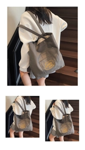Close-up of dark grey canvas tote bag featuring yellow embroidery and front patch pocket