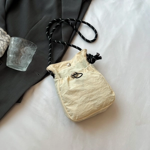 Détail du sac bandoulière en nylon beige avec poche à cordon et sangle tressée