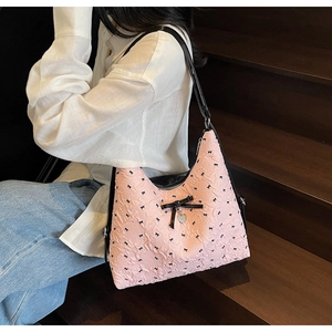 Detailed close-up of pink puff textured tote bag with black bow and silver heart charm