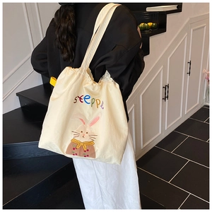 Close-up of beige canvas tote featuring embroidered rabbit patch and colorful lettering