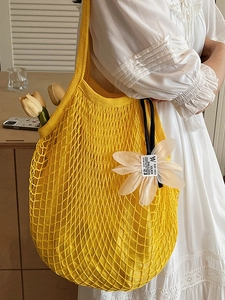 Leuchtend gelbe gehäkelte Netztasche mit Blumenanhänger für den Sommer am Strand