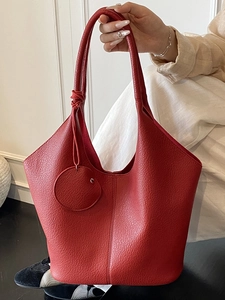 Deep red minimalist tote bag in pebbled leather with a matching small round pouch charm
