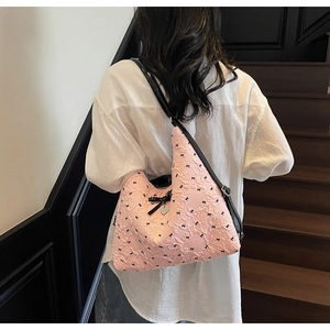 Detailed view of the pink bubble fabric with black bow patterns and a heart pendant charm