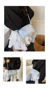 Detail of light blue polka dot baguette bag with letter B and pearl lace charm