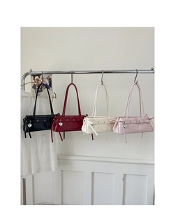 Row of faux leather baguette bags with side bows and metal heart charms hanging on a rack