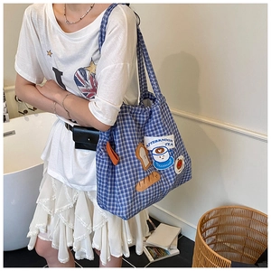 Close-up of blue checkered canvas tote bag with afternoon tea embroidery and orange handles