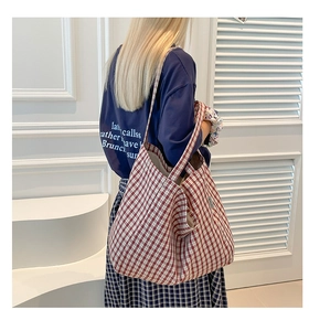 Détail macro du sac cabas en toile vichy rouge avec couture et étiquette latérale