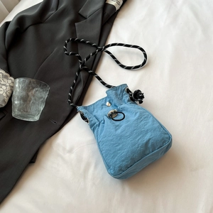 Détail du sac seau en nylon bleu clair avec bandoulière en corde tressée bicolore