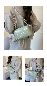 Detail of light green polka dot baguette bag featuring a pearl mesh pendant charm