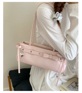 Detail of pink PU leather underarm bag with bow, heart pendant and metal eyelets