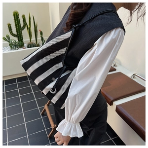 Detail showing the striped woven mesh tote bag with black shoulder strap and silver ring