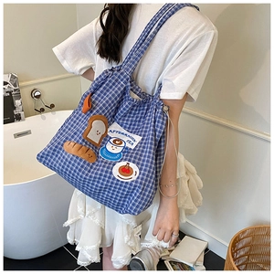 Detail of blue checkered tote bag with embroidered afternoon tea cartoon patches