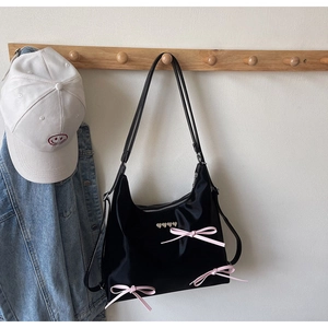 Close-up of black tote bag featuring pink silk bows and heart-shaped metal studs