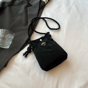Détail d'un sac à bandoulière en nylon noir avec cordon de serrage et boucle sur fond blanc
