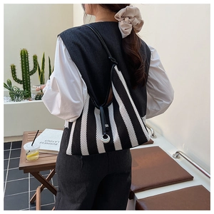 Close-up of black and white striped knit shoulder bag with sleek metal ring hardware