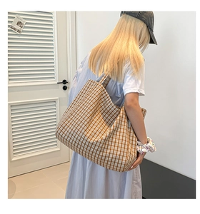Détail du grand sac cabas en toile à carreaux marron avec étiquette latérale tissée