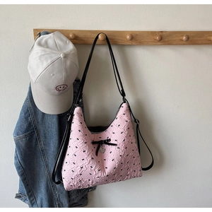 Detail of pink bubble texture tote bag with black bow print and heart metal charm