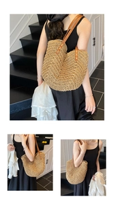 Detail of handwoven straw tote bag with brown leather straps and reinforced stitching