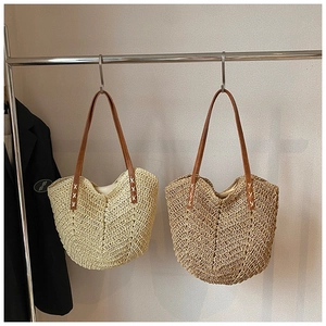 Detail of woven straw tote bags in beige and wood tones with brown leather straps