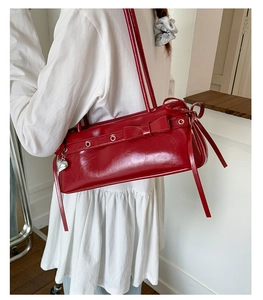 Red patent leather crossbody bag with bow decoration and heart pendant on shoulder