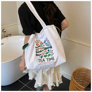 Detail of white canvas tote bag featuring floral tea time print and drawstring closure