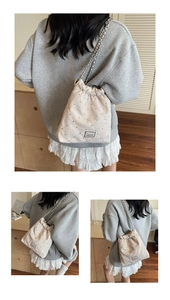 Detail view of cream quilted bucket bag with silver rivets and metal chain strap