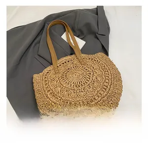 Detail showing woven hollow straw texture and reinforced leather shoulder straps of beach bag