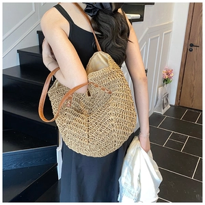Close-up of natural woven straw tote bag texture with brown leather shoulder straps