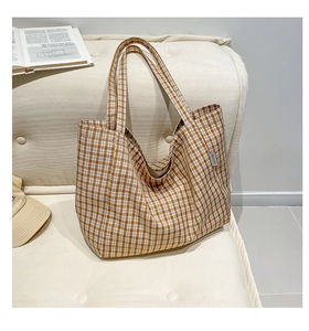 Gros plan du sac cabas en toile à carreaux marron avec logo sur un canapé