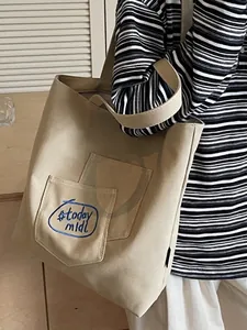 Minimalist khaki canvas tote bag with blue embroidered pocket for daily casual use