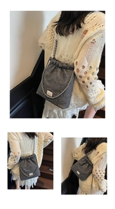 Detailed view of dark grey quilted bucket bag featuring white bead accents and chain strap