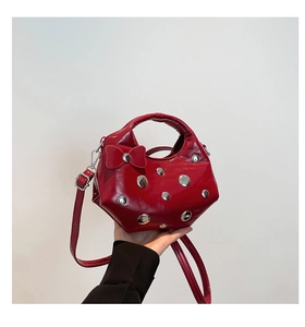 Detail of red patent leather crescent bag with silver studs and bow accent decoration