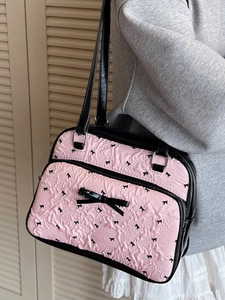 Pink pleated shoulder bag with black bow patterns and 3D bow detail on model