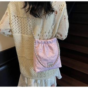 Detail of pink quilted bucket bag with mini studs and gold chain strap on a model
