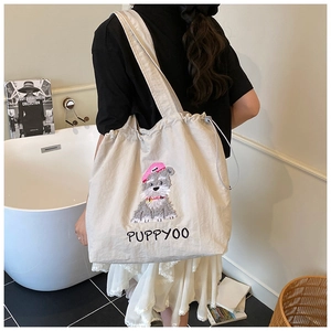 Detailed view of beige canvas tote bag featuring dog embroidery and drawstring closure
