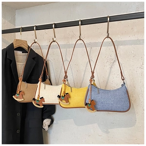 Detail of four textured fabric crescent bags with brown piping and wooden charms