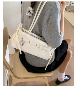 Detail of white patent leather shoulder bag with bow knot and silver heart pendant