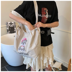Detail of drawstring tote bag with schnauzer embroidery and black lettering on off-white fabric