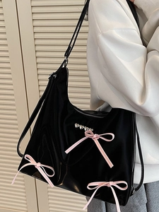 Fashionable black hobo tote bag with pink bows and silver heart accents on model
