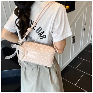 Pink polka dot baguette bag with white bow and pearl pendant details shown in use
